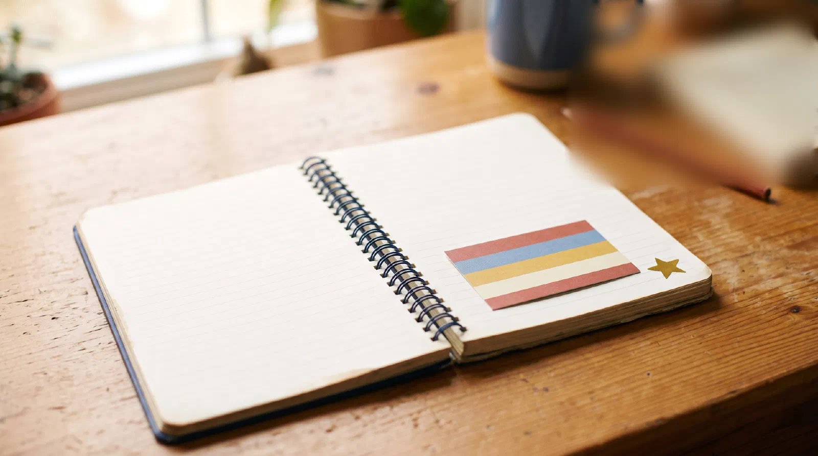 A small colorful blank ticket card tucked into a notebook on a student desk with a gold star sticker beside it